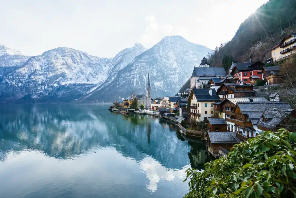 beautiful-shot-small-village-surrounded-by-lake-snowy-hills.webp